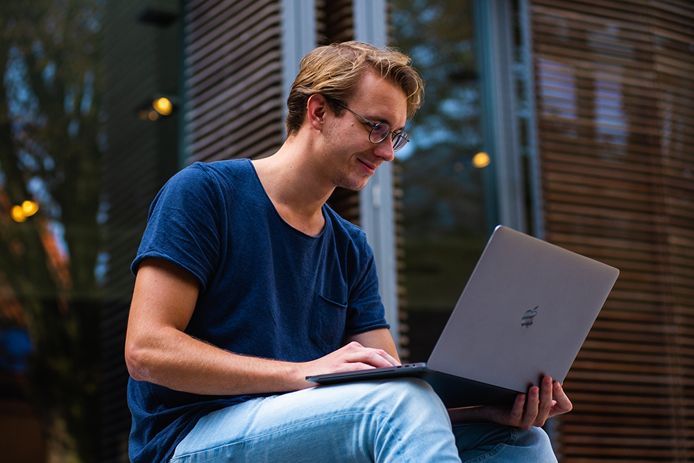 Man with a MacBook sitting in stairs outdoor