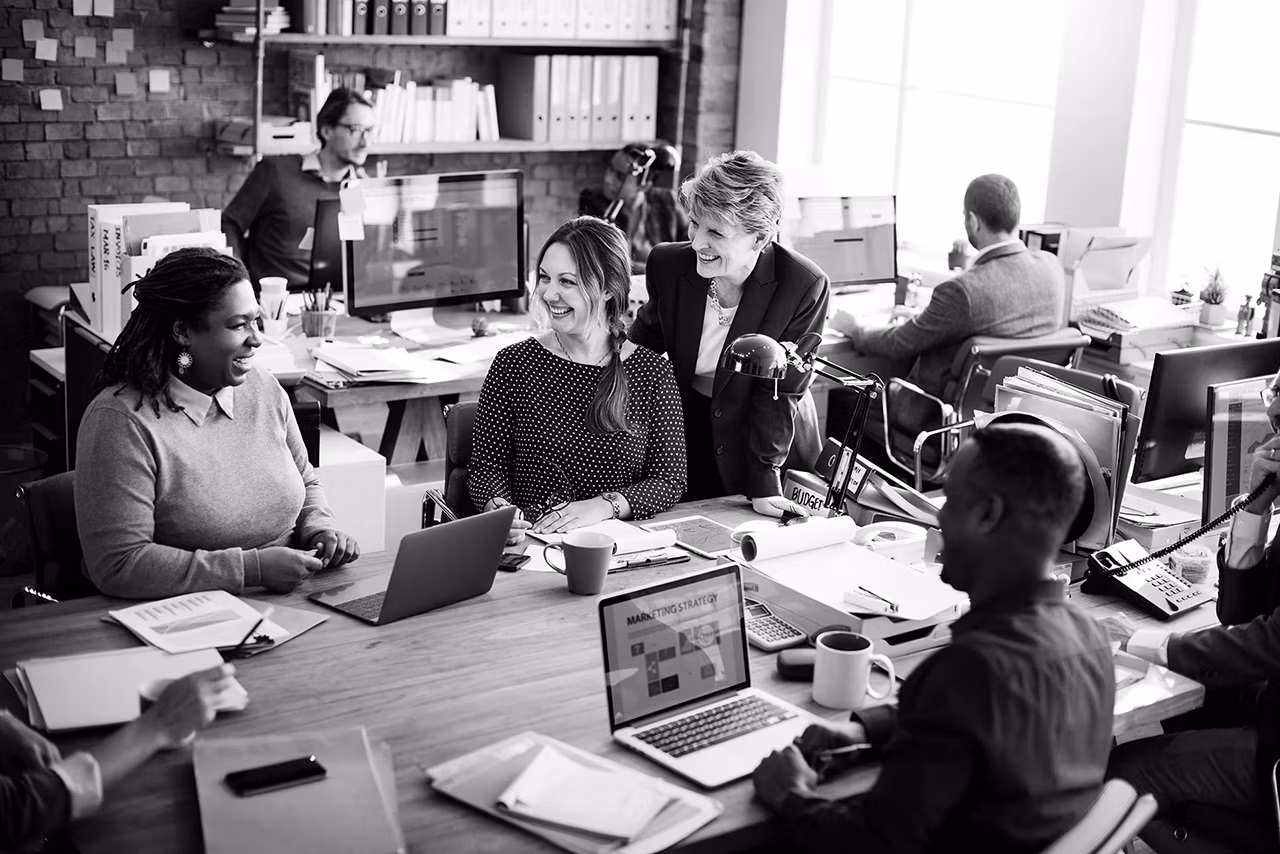 Group of people in a modern office using Mac computers.