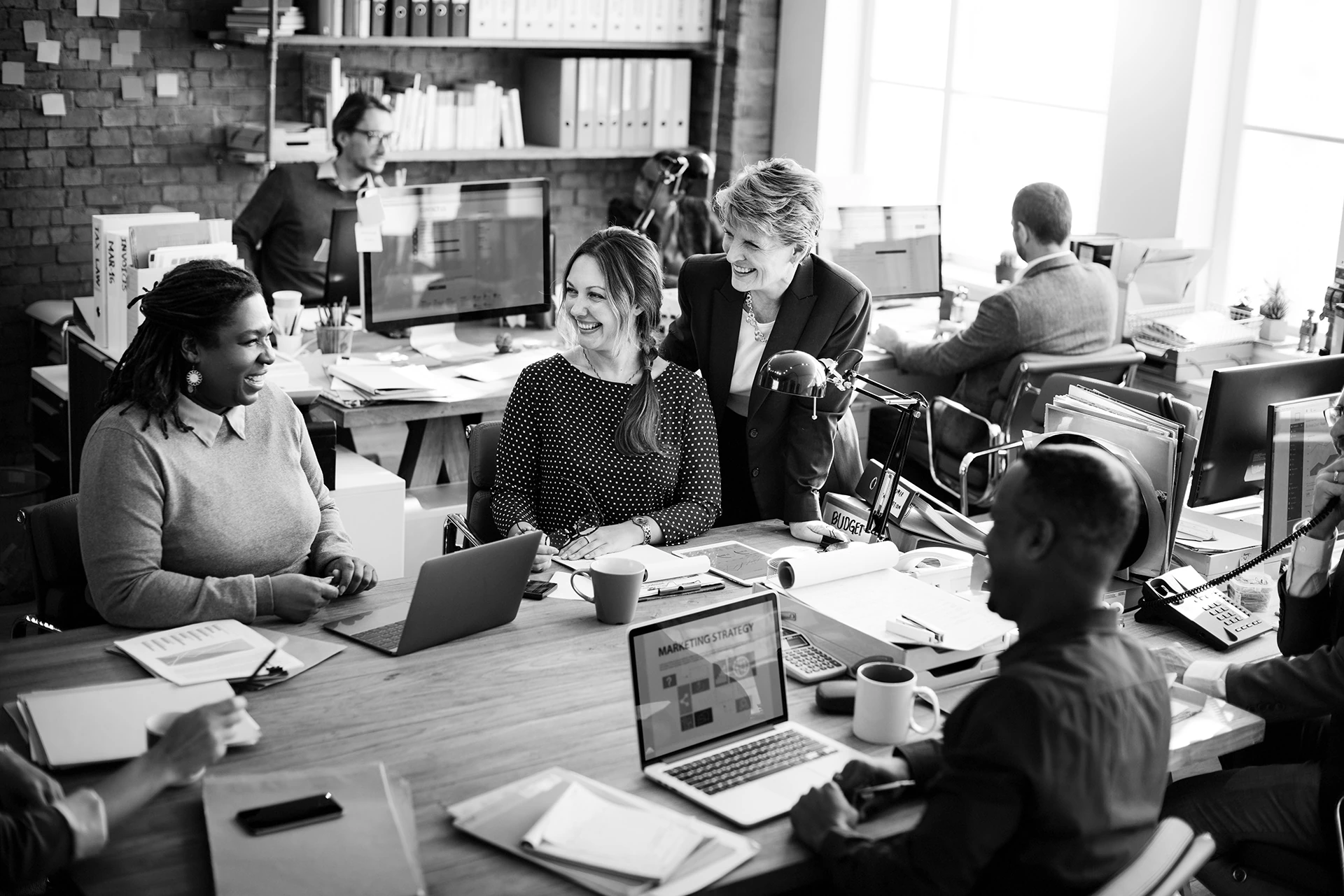 Group of people in a modern office using Mac computers.