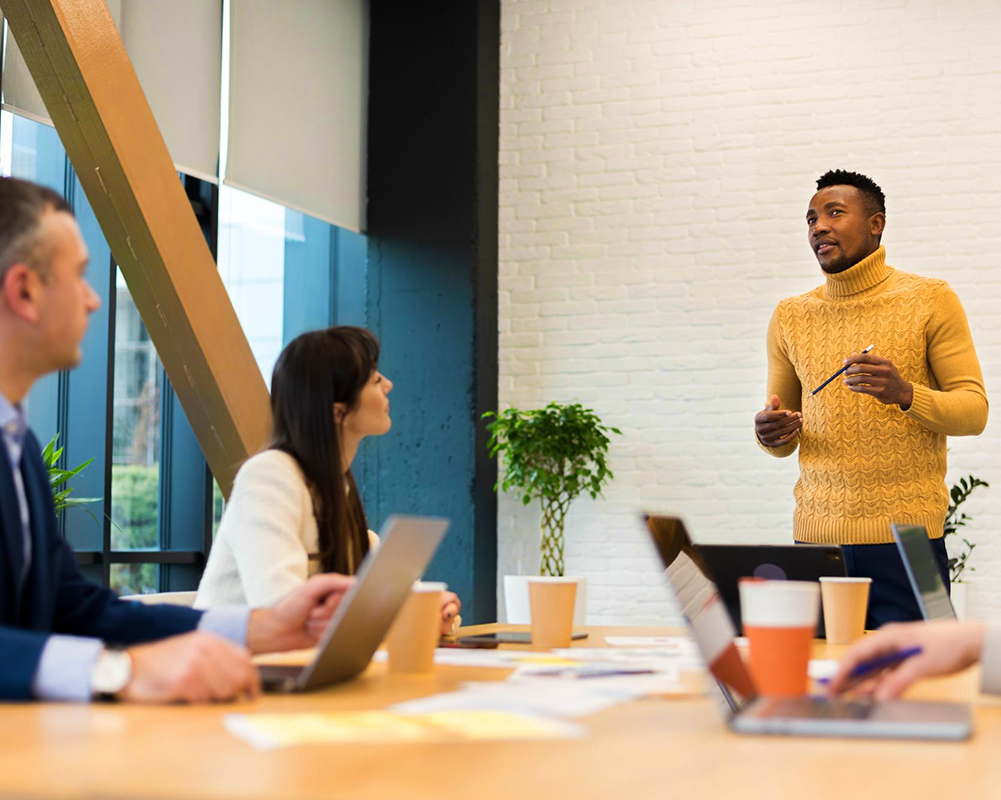 People attending a meeting with several Mac computers on the table