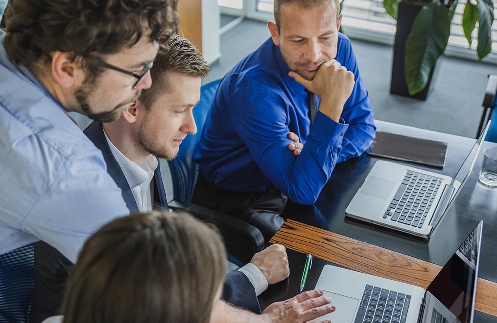 Group of people checking work on a MacBook computer