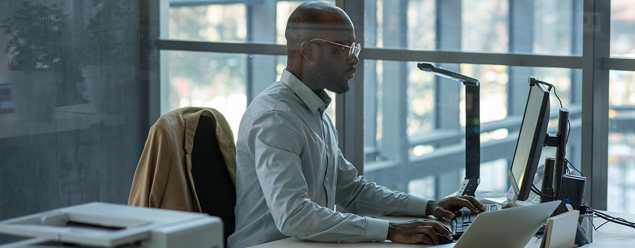 Executive working on a Mac computer in an glass office