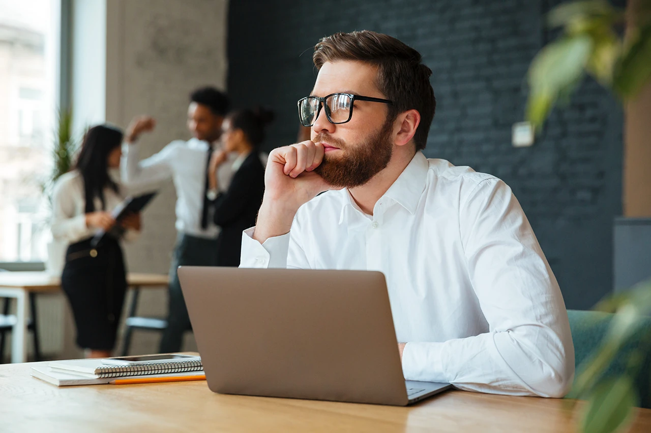 Man doing some thinking in front of a Mac computer