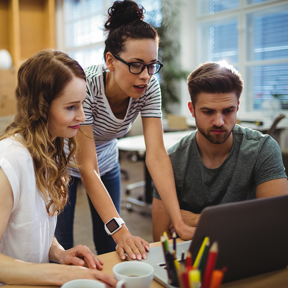 Group of people discussing a project on a Mac computer